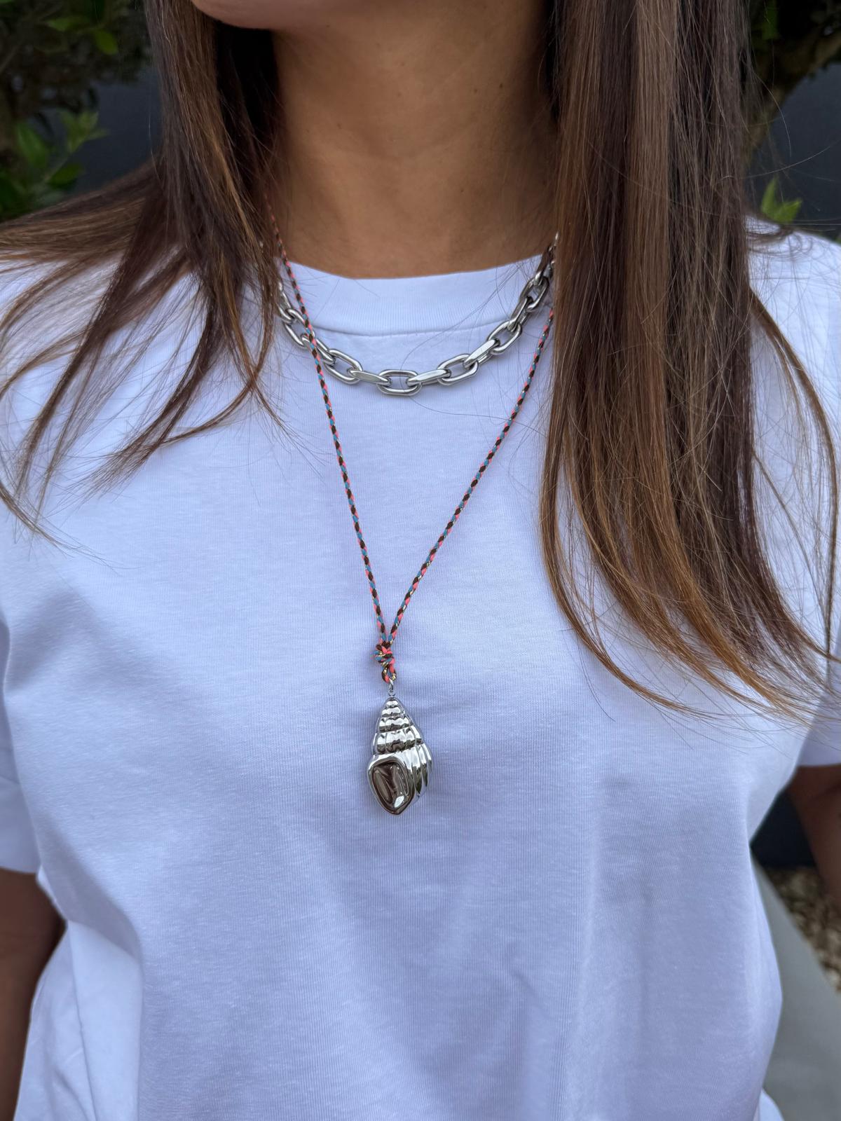Colares com concha metálica e corrente prateada em pessoa com t-shirt branca