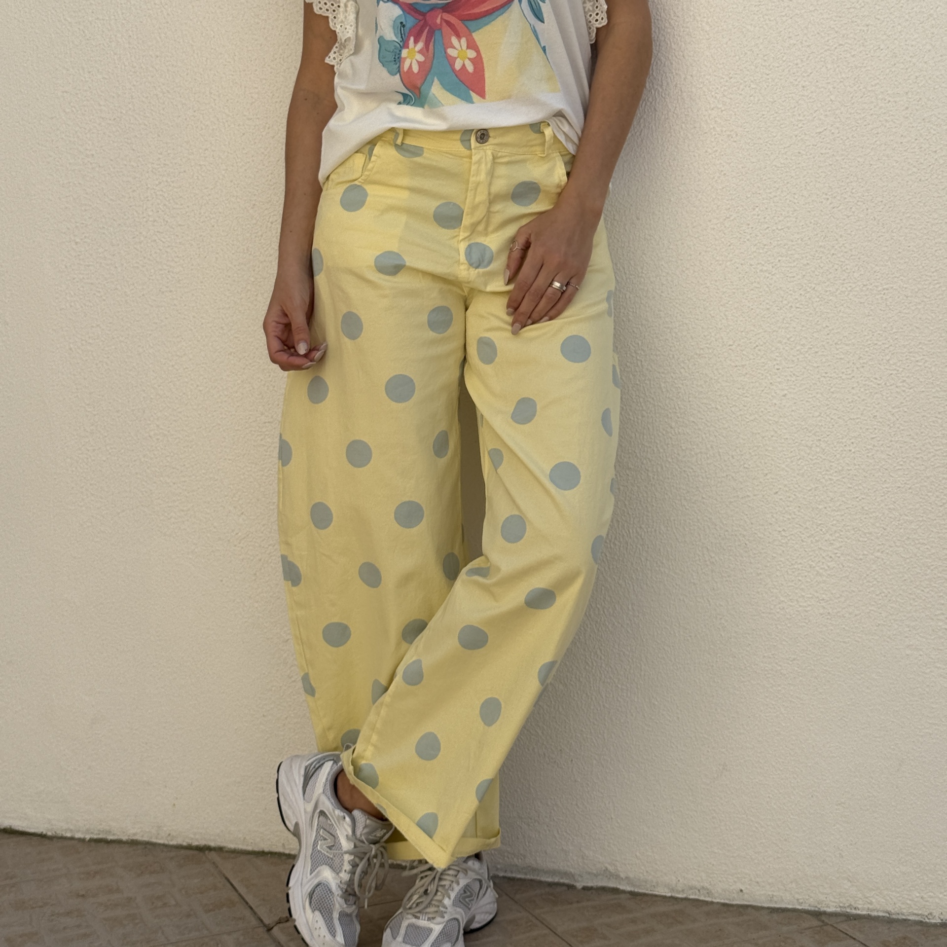 Calças amarelas com bolas cinzentas e sapatilhas brancas e cinzentas