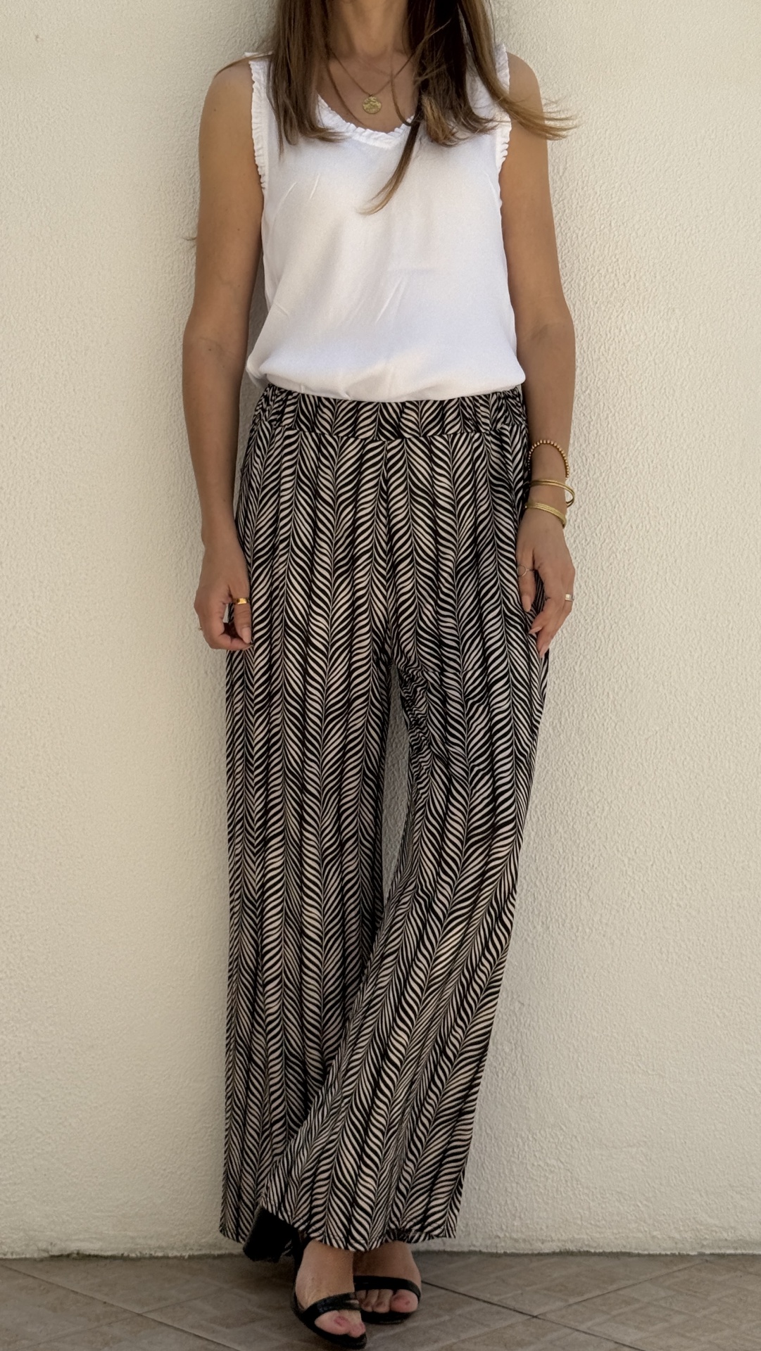 Conjunto feminino com camisola branca e calças largas estampadas em padrão geométrico.