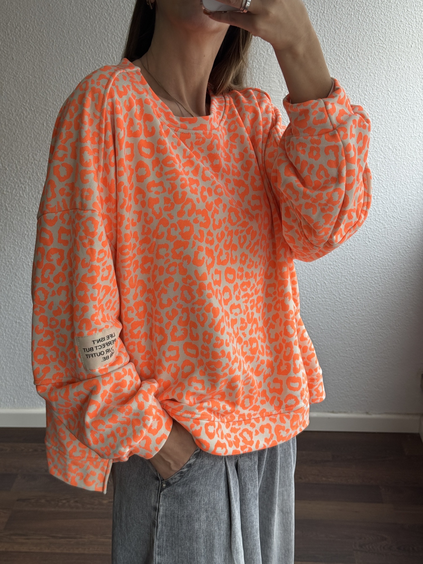 Sweatshirt feminina laranja com padrão animal print e etiqueta no braço
