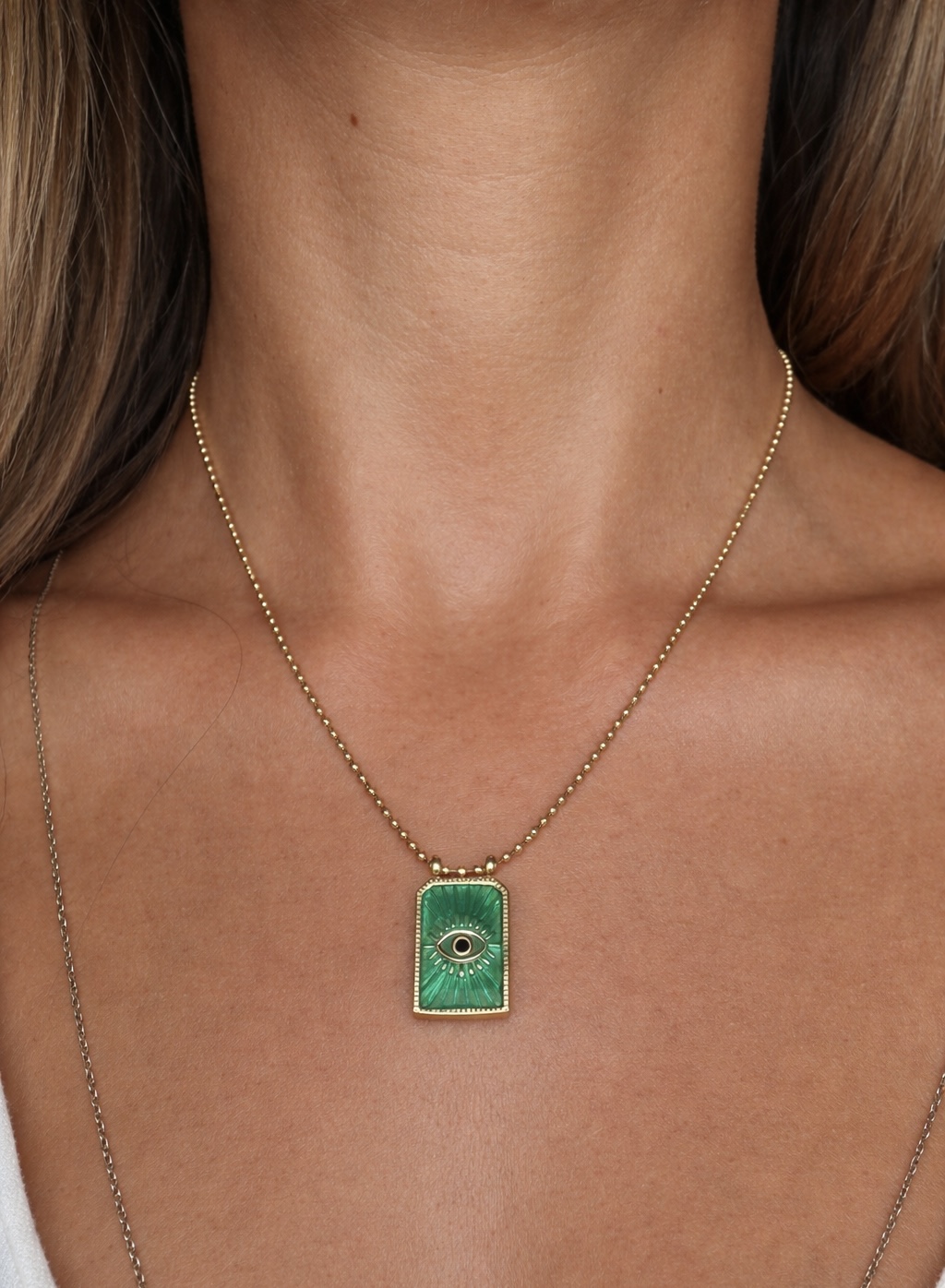 Colar dourado com pendente verde retangular com desenho de olho