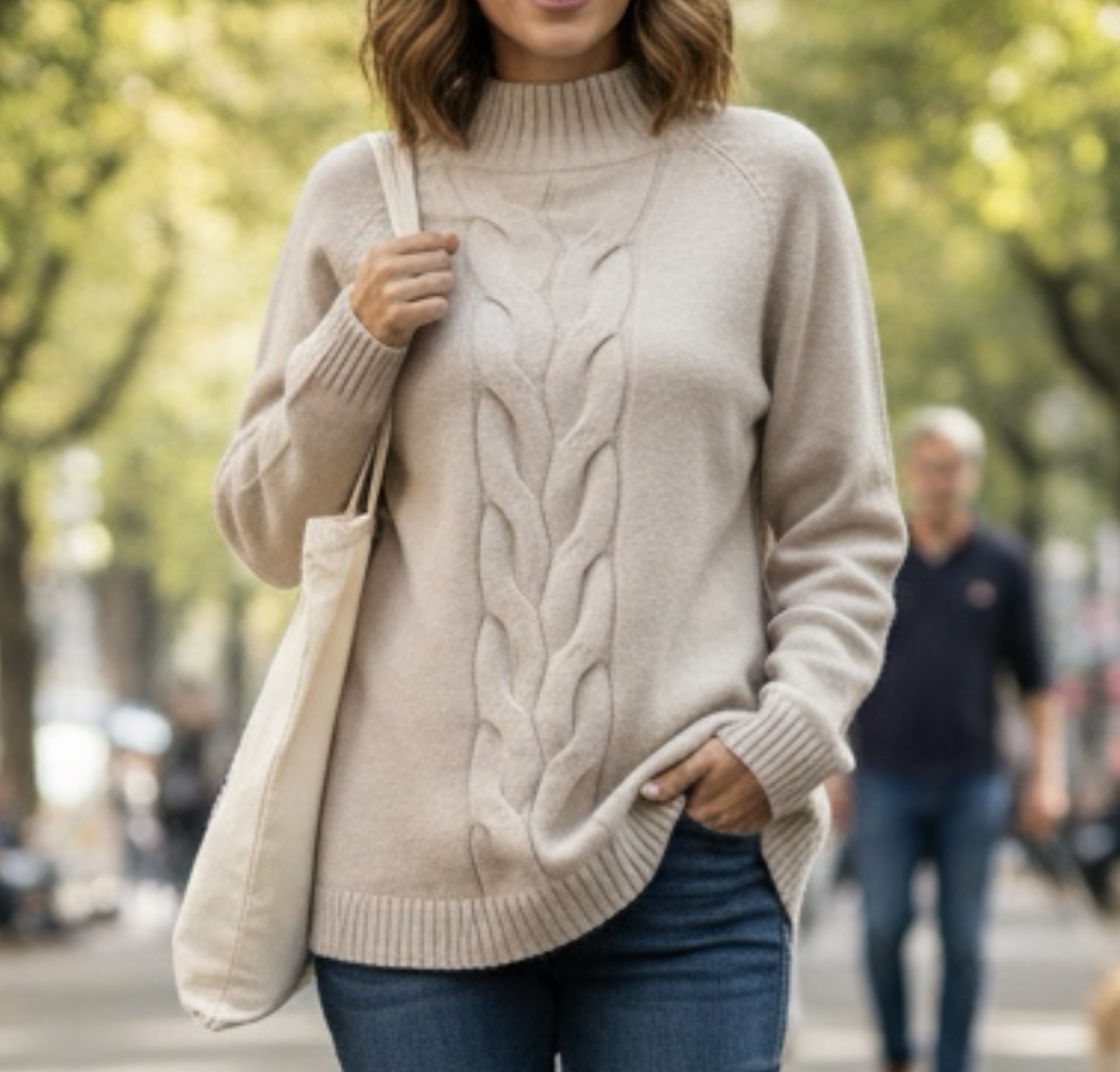 Mulher de camisola bege com padrão trança e calças jeans
