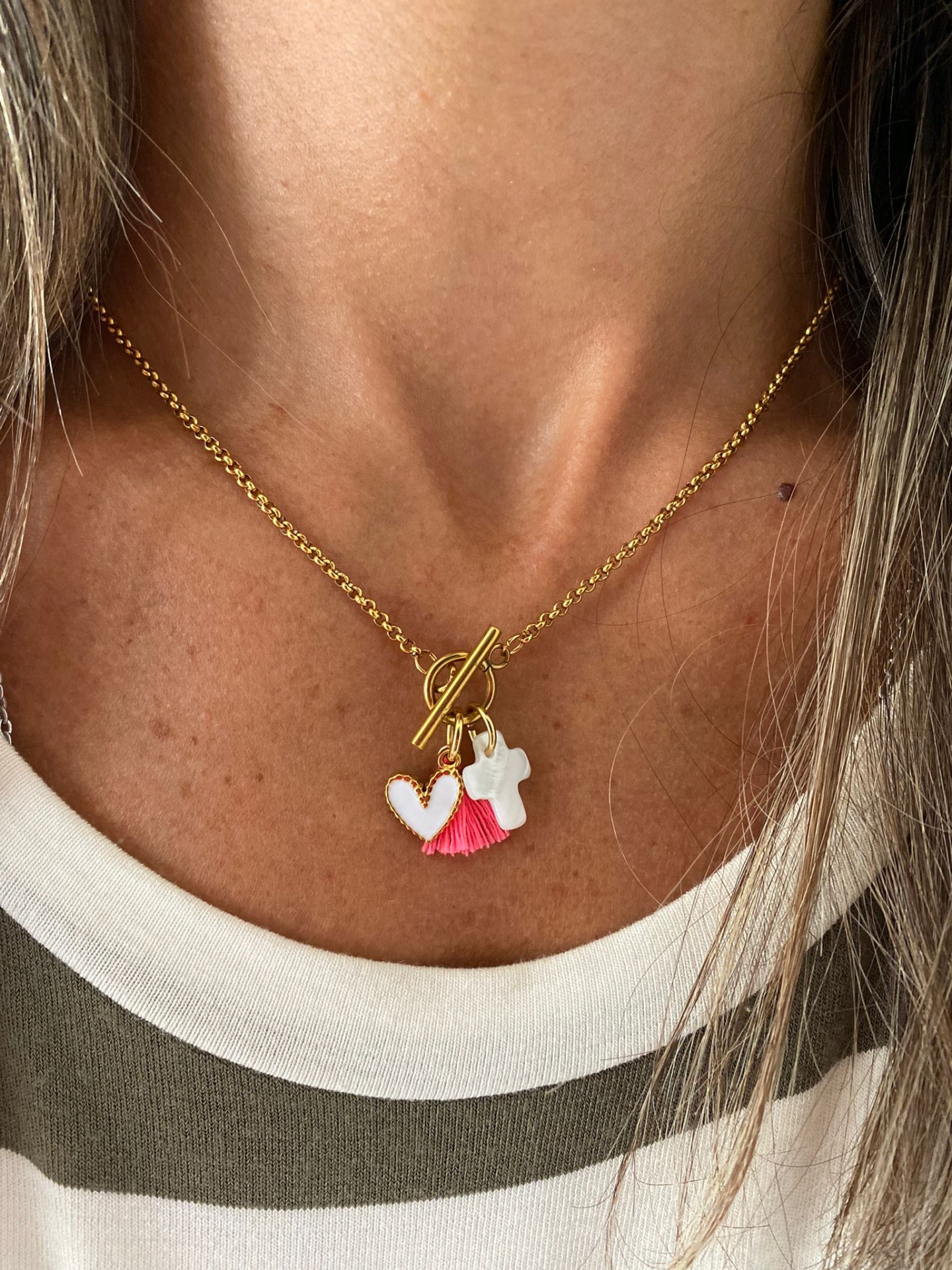 Colar dourado com três pendentes, usado ao pescoço.