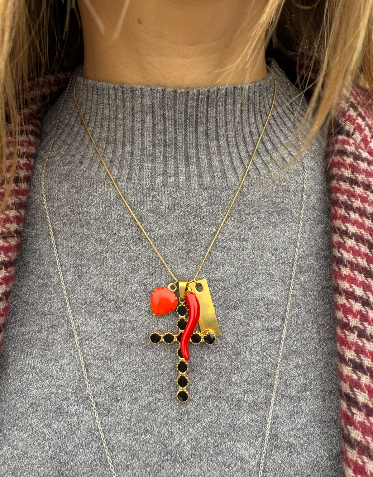 Colar com pendentes em diferentes formas e cores sobre camisola cinzenta e casaco às riscas.