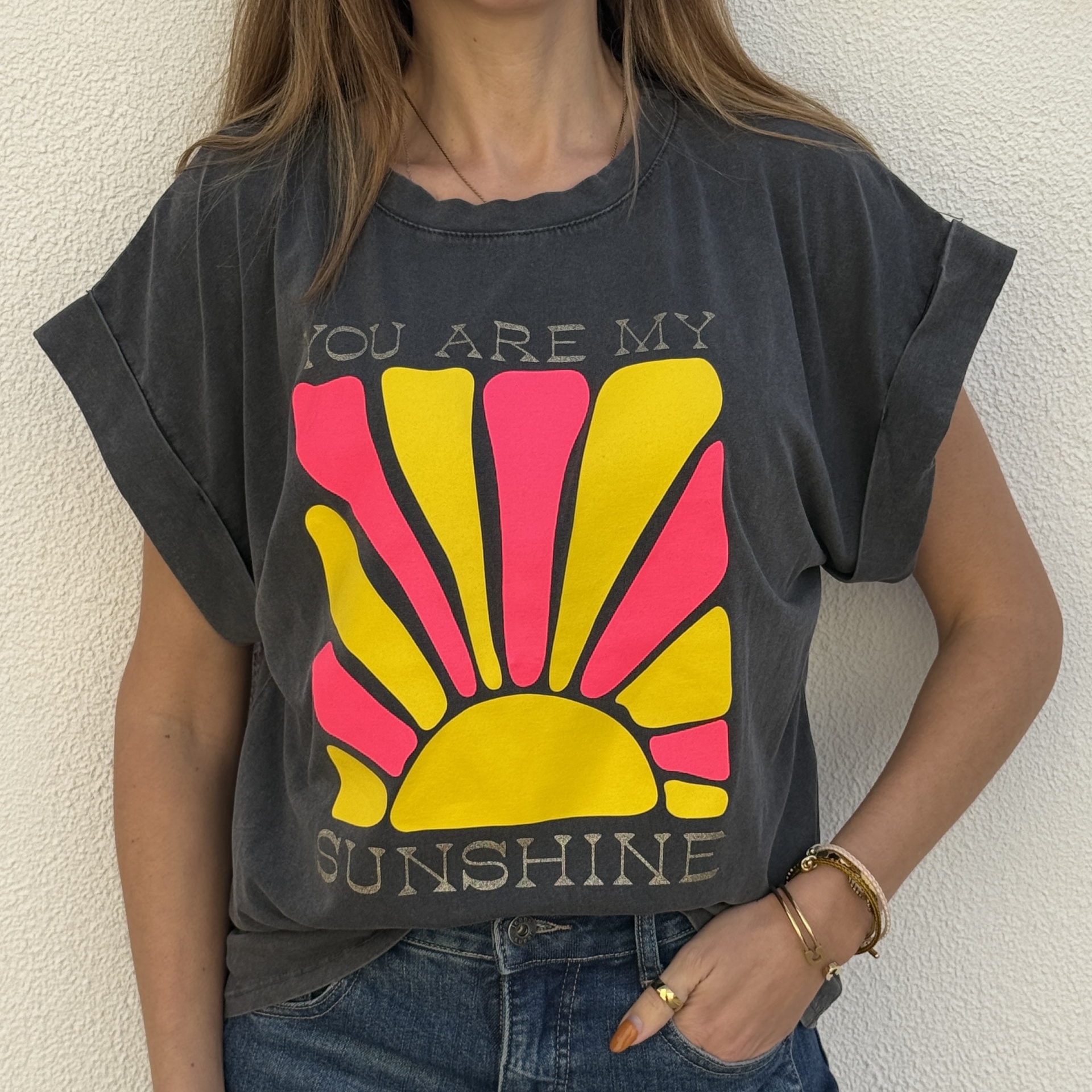 T-shirt cinzenta escura com estampa de sol amarelo e rosa e texto em inglês