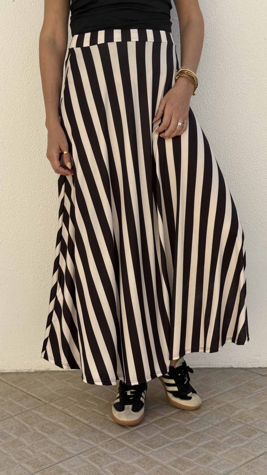 Saia comprida às riscas diagonais preto e branco com sapatilhas desportivas.