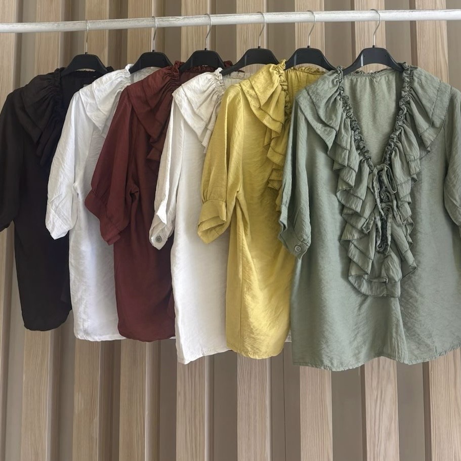 Seis blusas femininas com folhos em várias cores penduradas no cabideiro