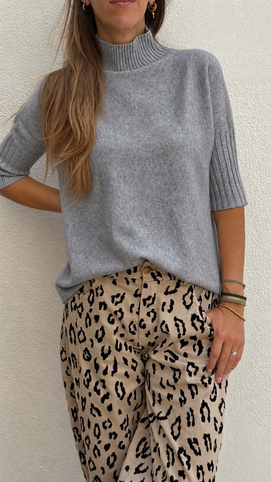 Blusa cinza de malha com gola alta e calças bege com padrão animal print.