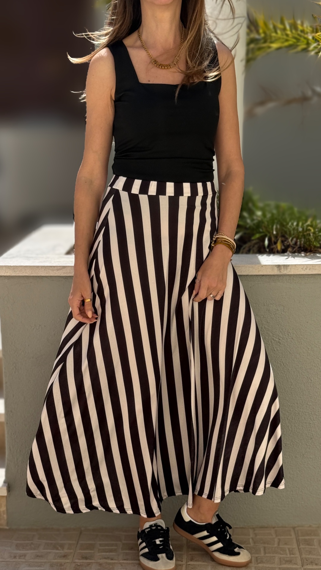 Saia midi riscas pretas e brancas, top preto, tênis preto e branco, acessórios dourados