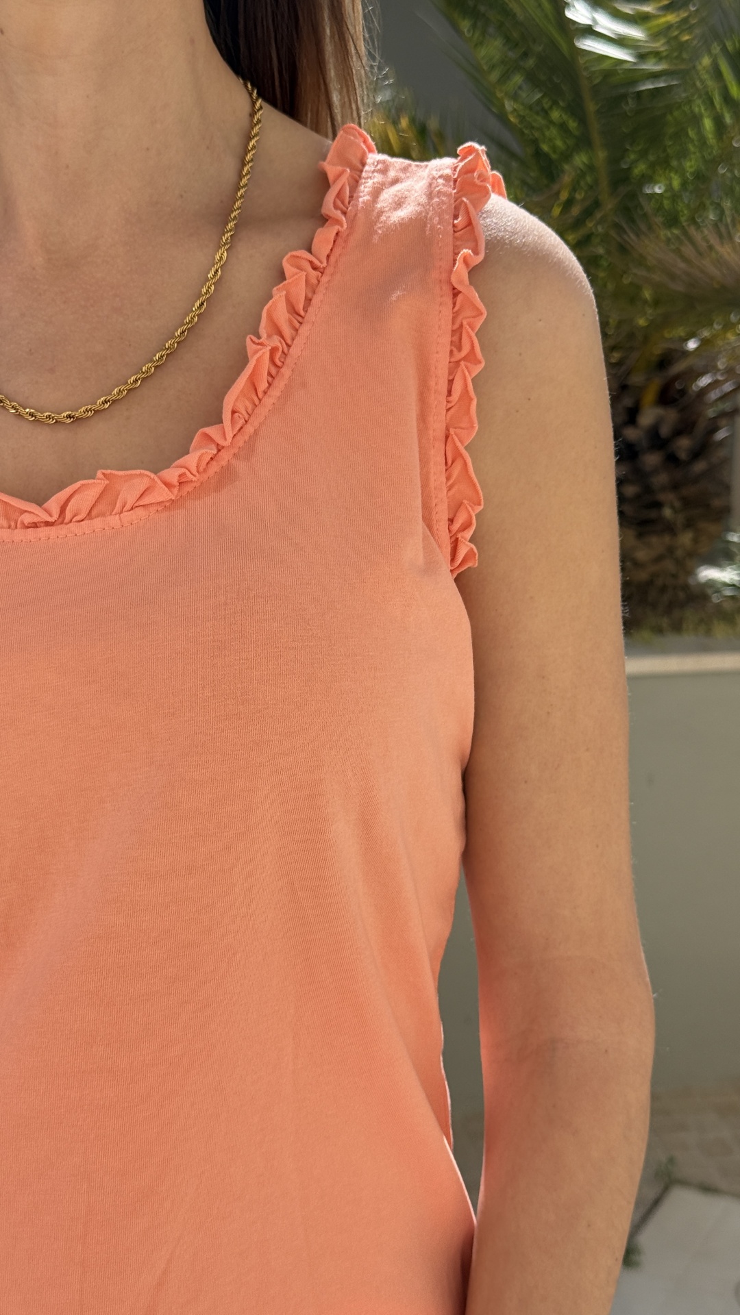 Top cor de pêssego com folhos e colar dourado em ambiente externo