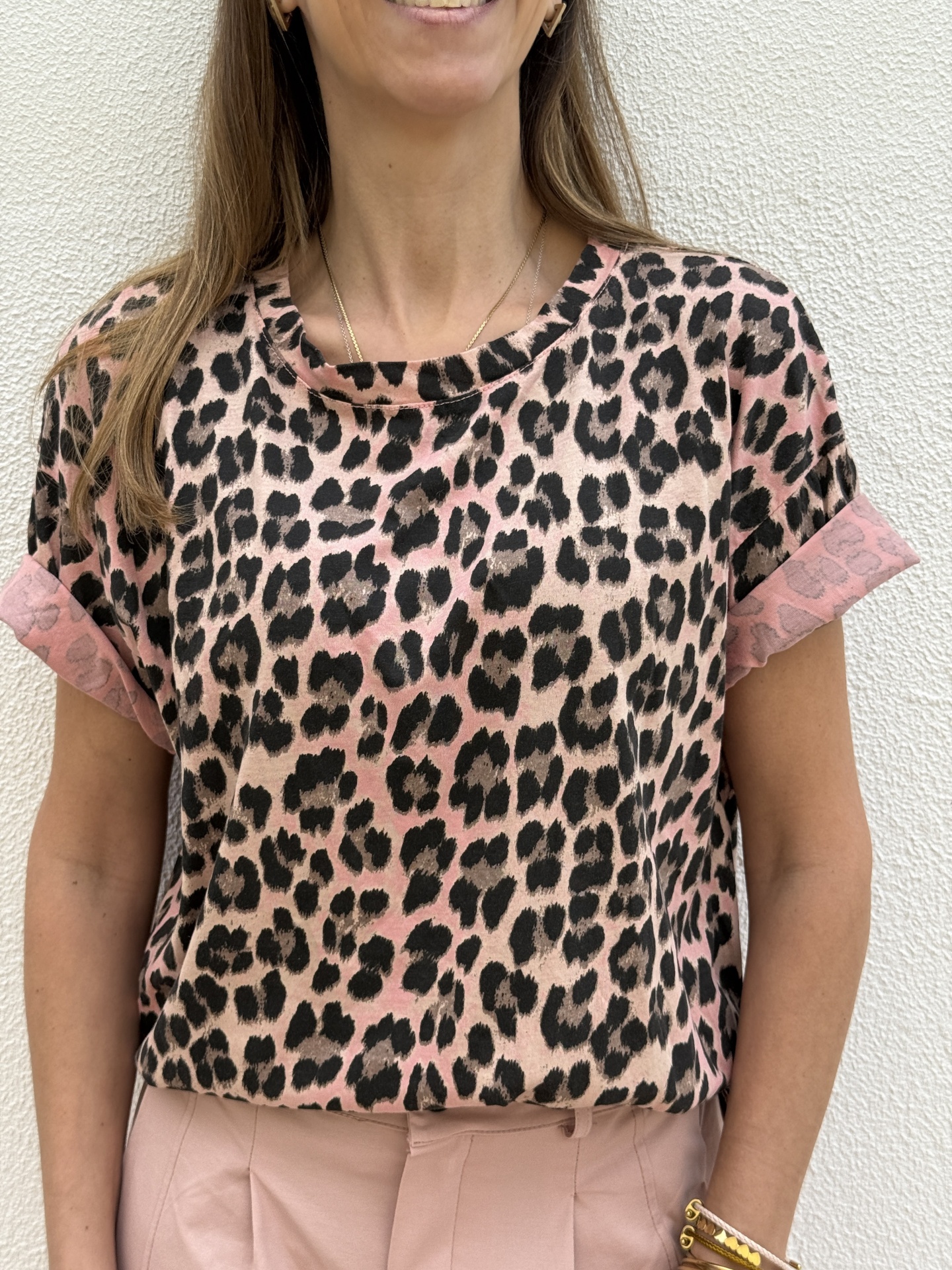 T-shirt animal print rosa e bege com calças rosa claro num fundo branco.