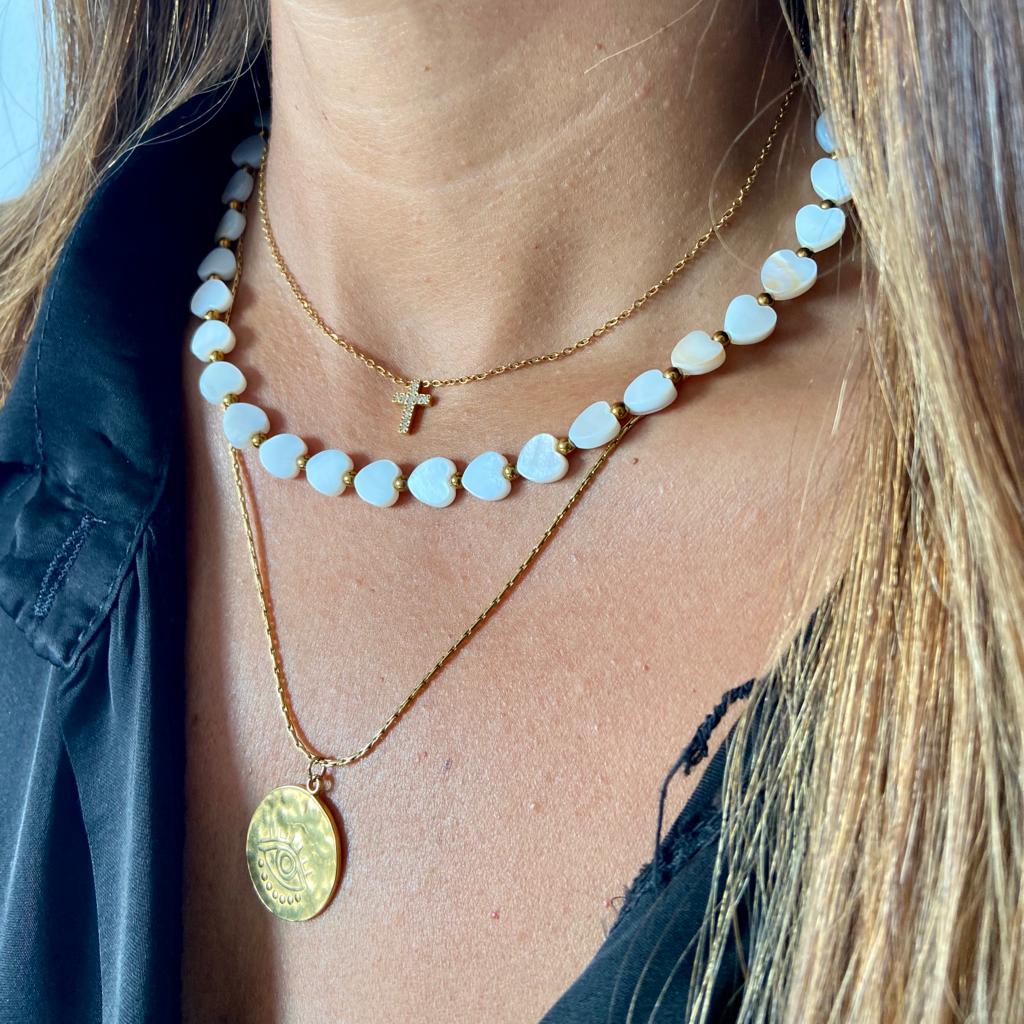 Três colares dourados e branco com contas em forma de coração usados no pescoço