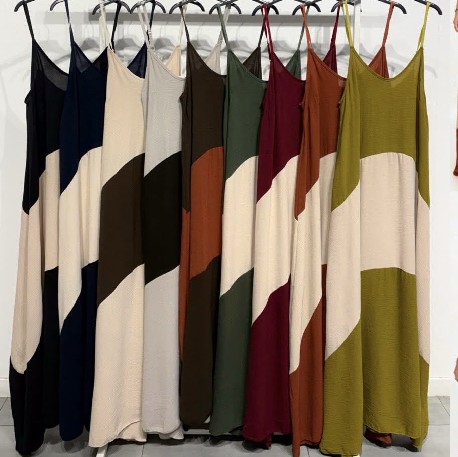 Vestidos compridos coloridos com padrão bicolor pendurados em cabides.