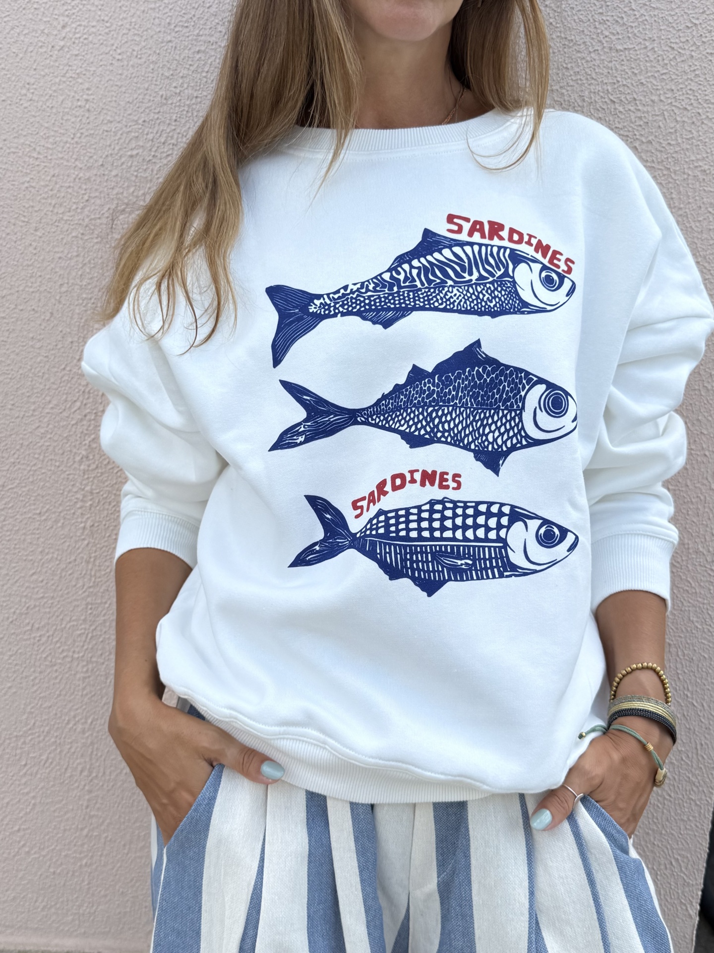 Sweatshirt branca com estampa azul de três peixes e texto vermelho