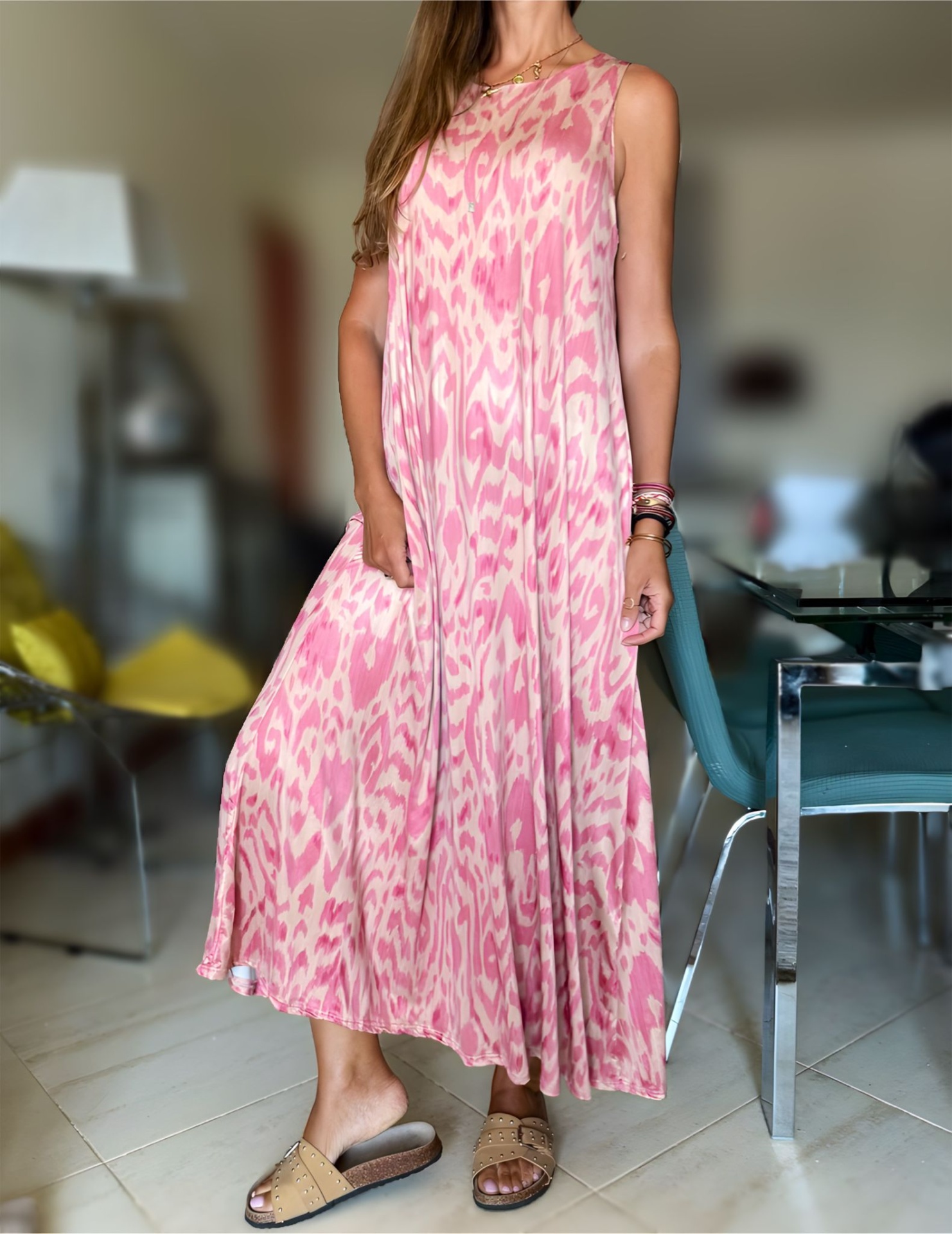 Vestido comprido rosa e creme com padrão, usado por pessoa em ambiente interior.