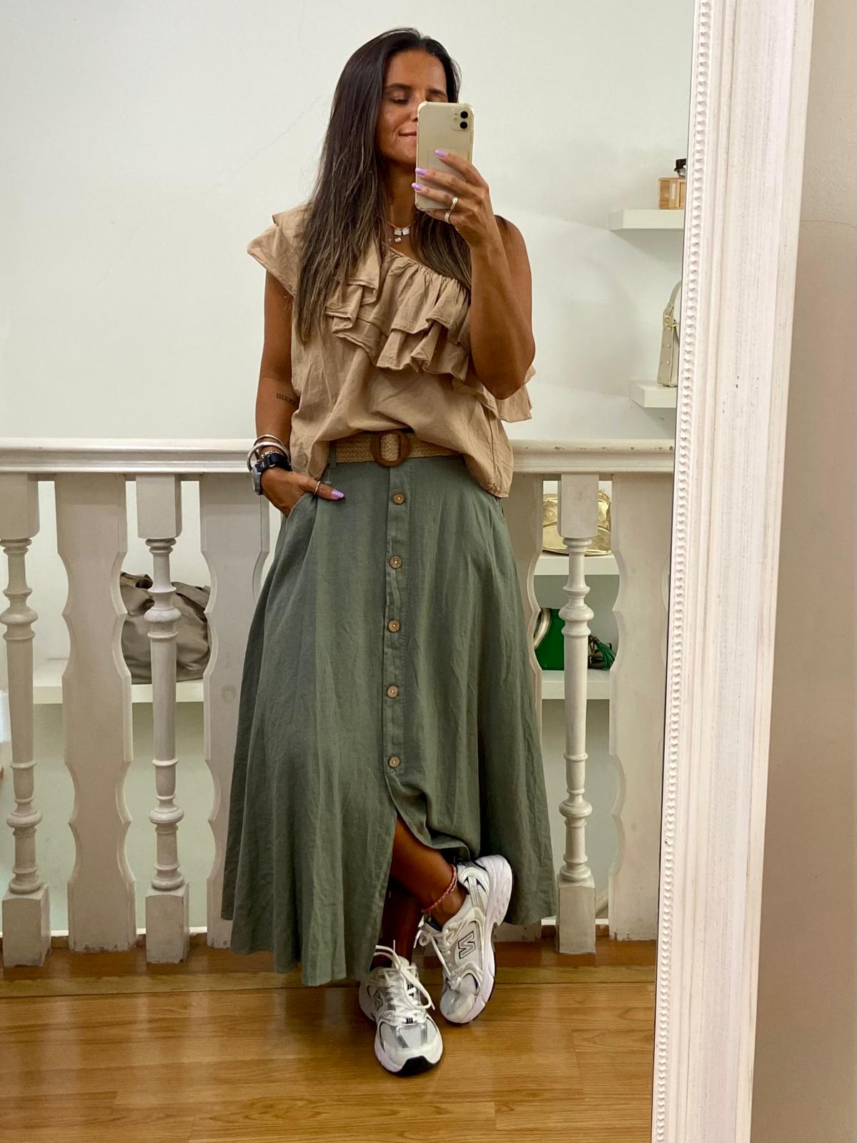 Roupa feminina casual com saia verde e top bege com folhos, em ambiente interior com espelho