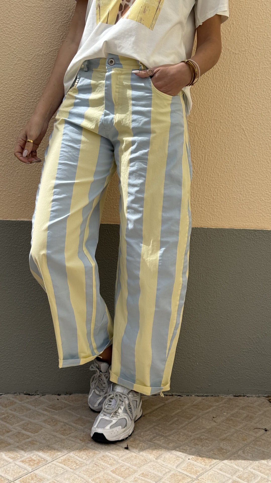 Pessoa a usar pantalonas às riscas, t-shirt branca e sapatilhas brancas