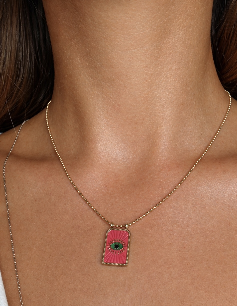 Colar dourado com pendente retangular rosa e olho verde no pescoço