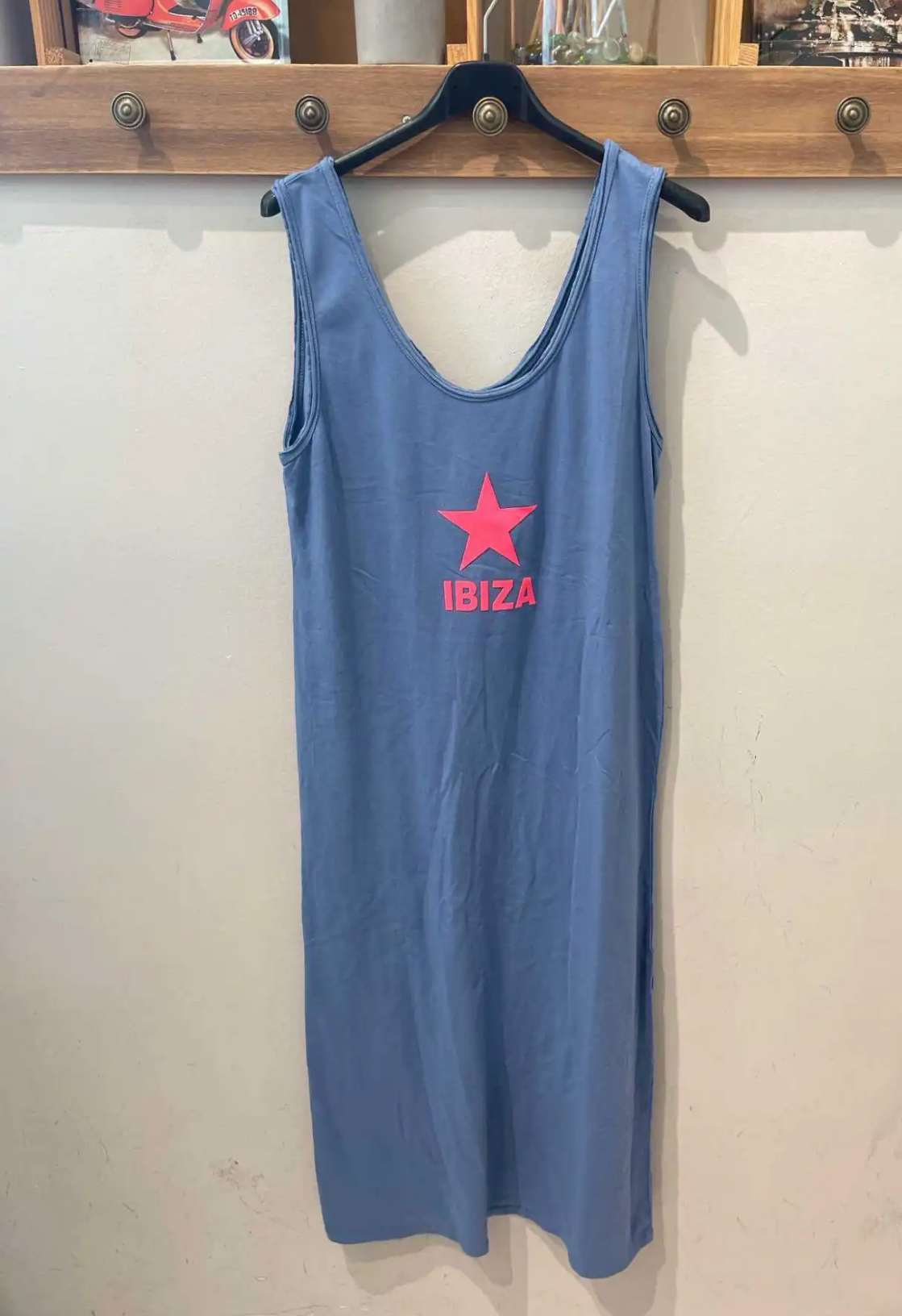 Vestido azul com estampa rosa IBIZA pendurado numa parede