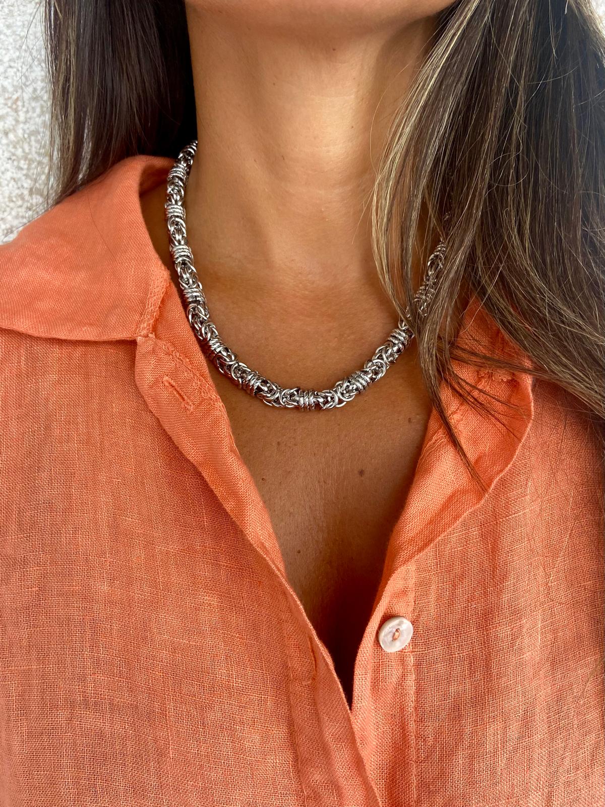 Colar de corrente prateada usado com camisa laranja de linho