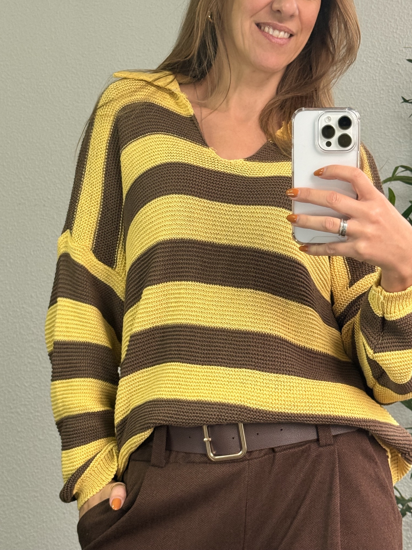 Camisola às riscas amarelas e castanhas com capuz, usada com calças castanhas e cinto castanho.