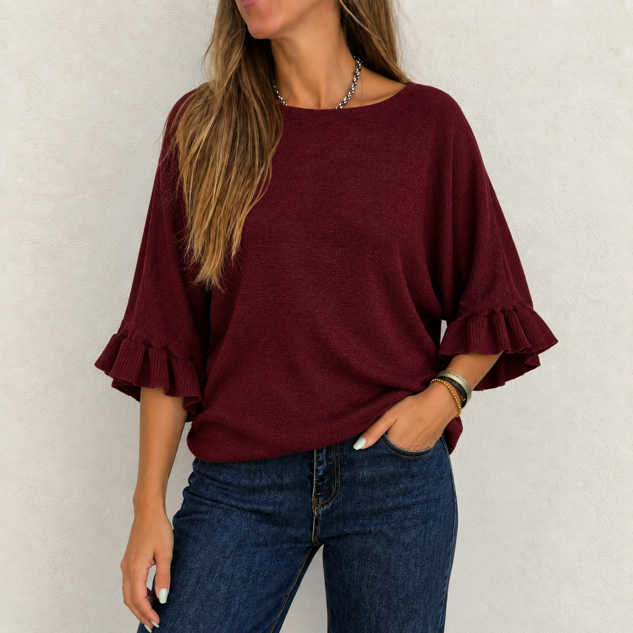 Camisola feminina vinho com mangas 3/4 e folhos, usada com jeans azul escuro, fundo branco