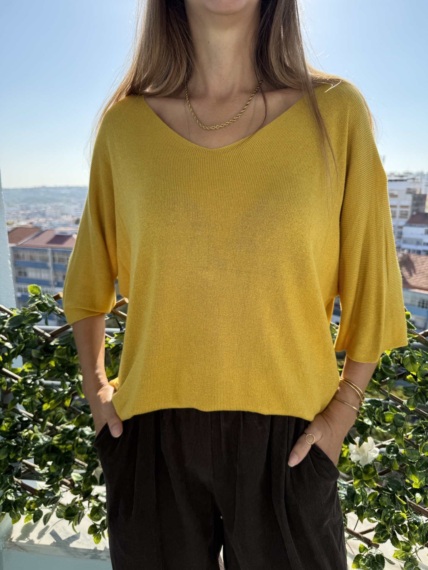 Top amarelo de malha com decote em V e mangas 3/4 soltas com calças pretas