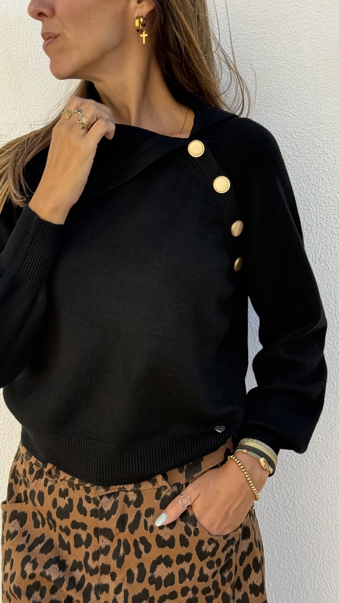 mulher a usar camisola preta com botões dourados e calças padrão leopardo