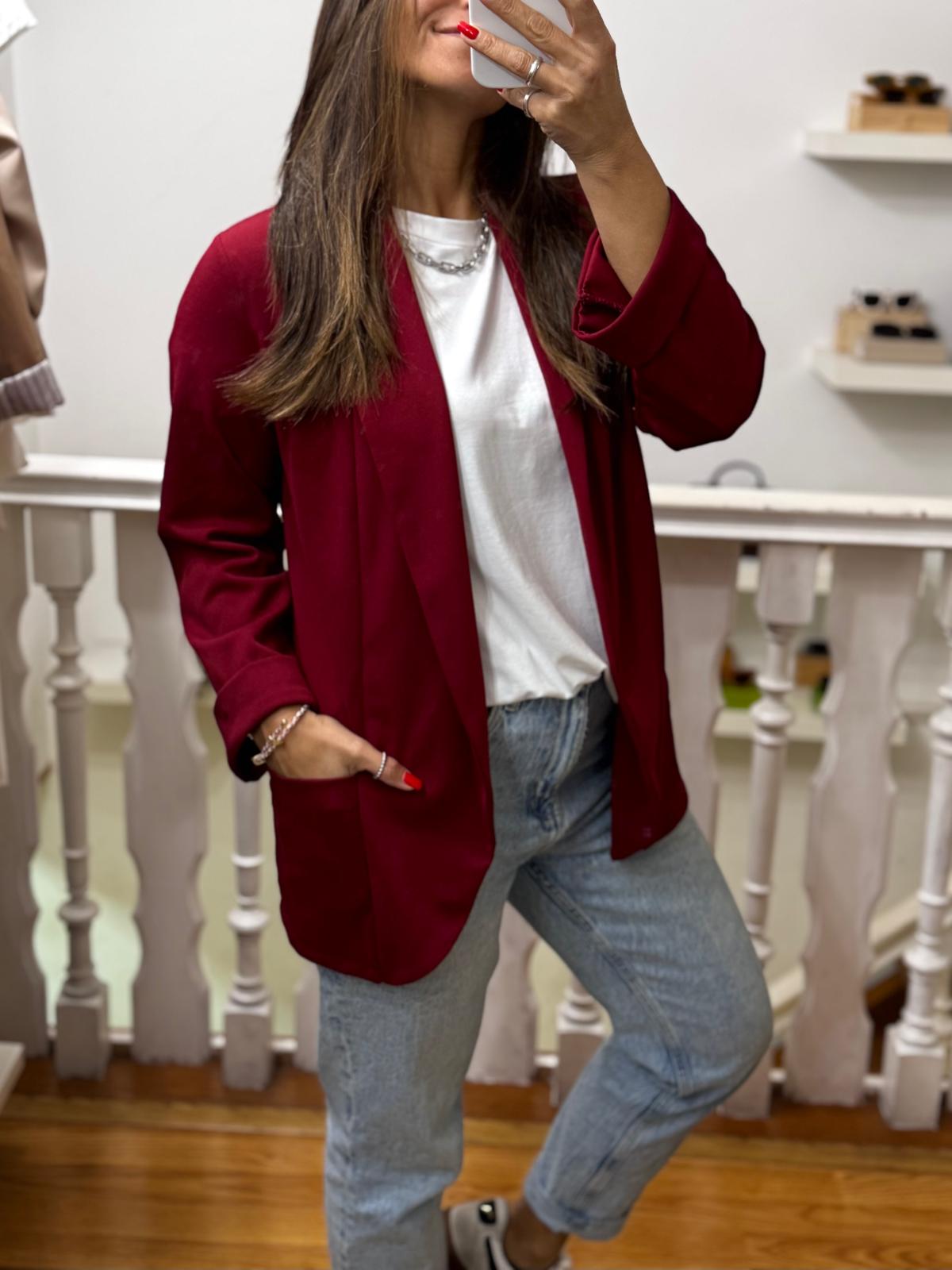 Mulher a vestir casaco vermelho, t-shirt branca, jeans azuis e ténis brancos