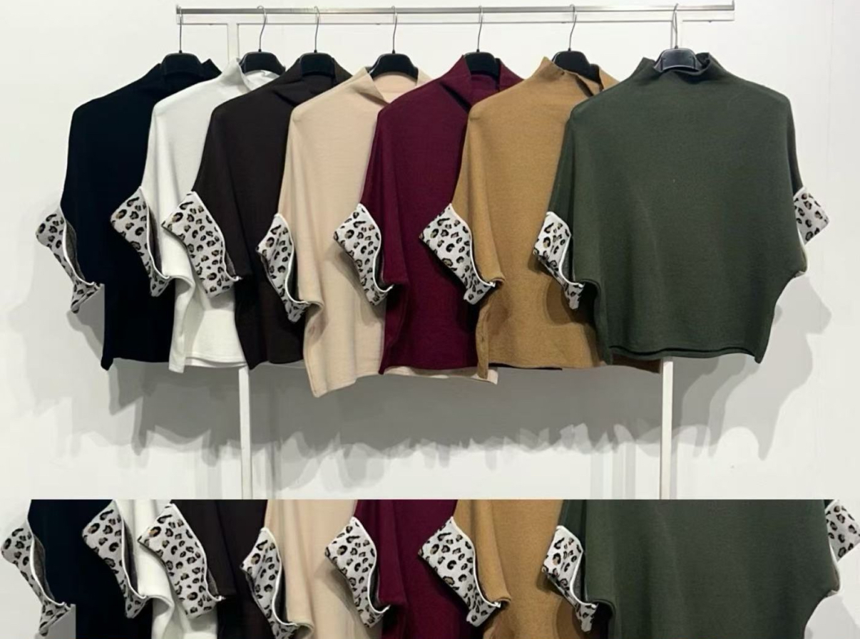 Sete blusas de malha curta com manga detalhe animal preto e branco penduradas num cabide.