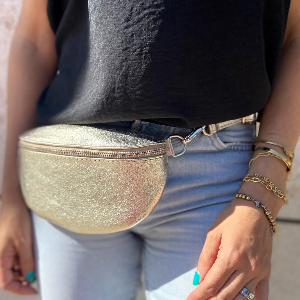 Pochete dourada brilhante usada à cintura com roupa casual e pulseiras