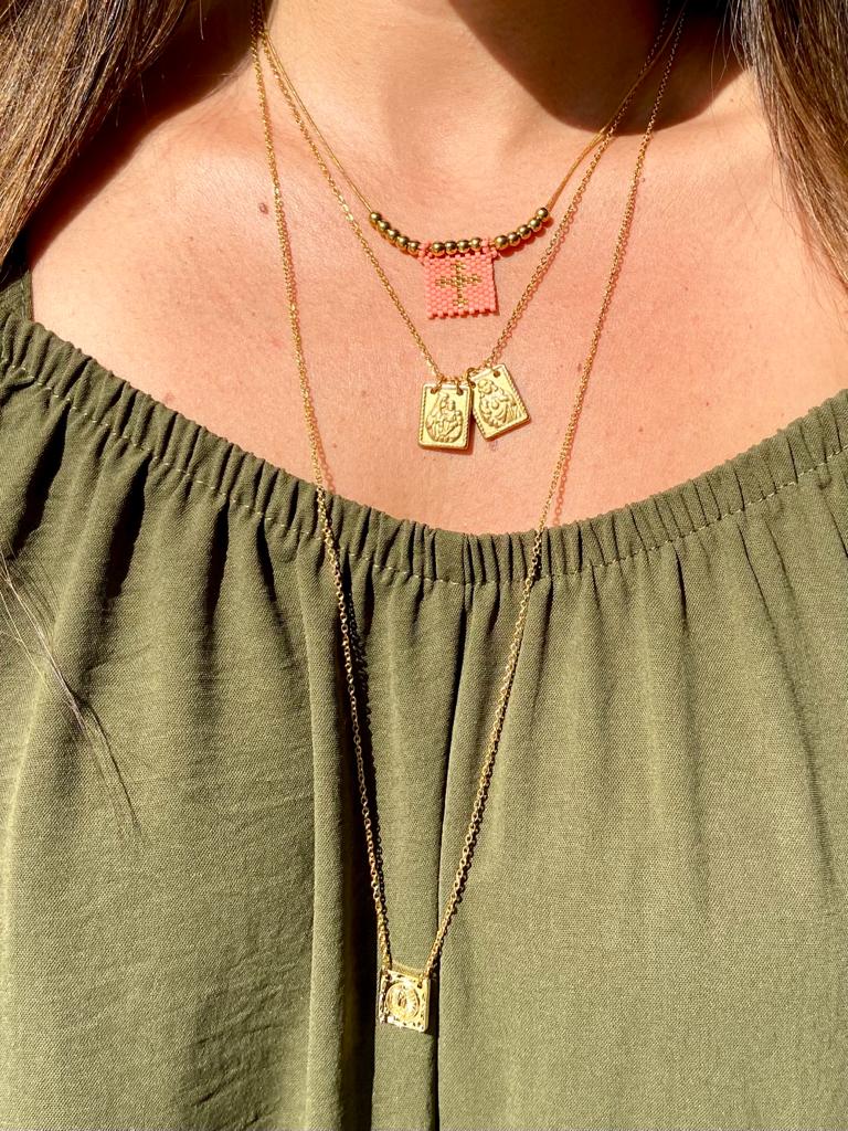 Colares dourados femininos usados sobre blusa verde com decote franzido