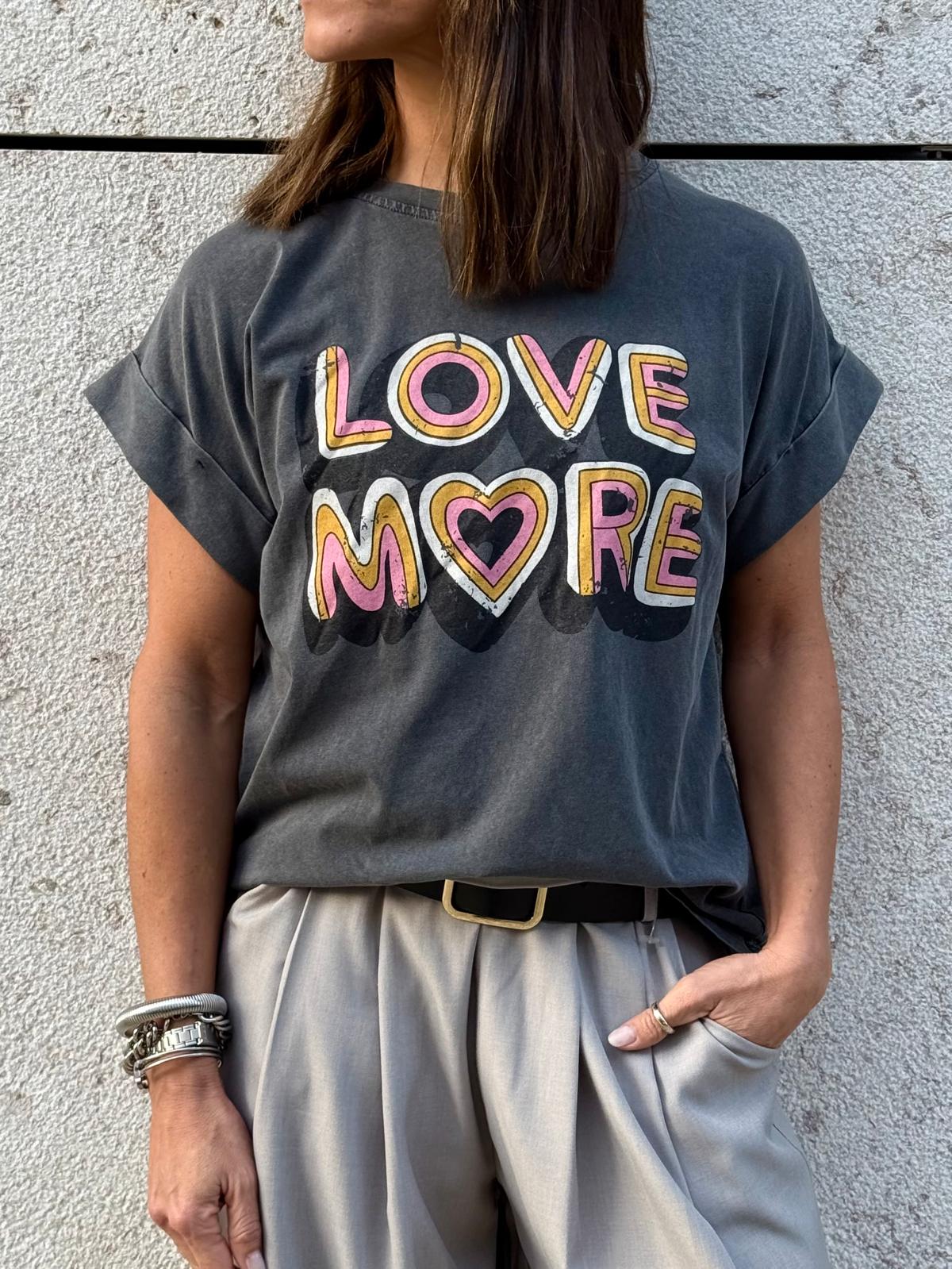 T-shirt cinza escuro com texto colorido LOVE MORE e calças claras
