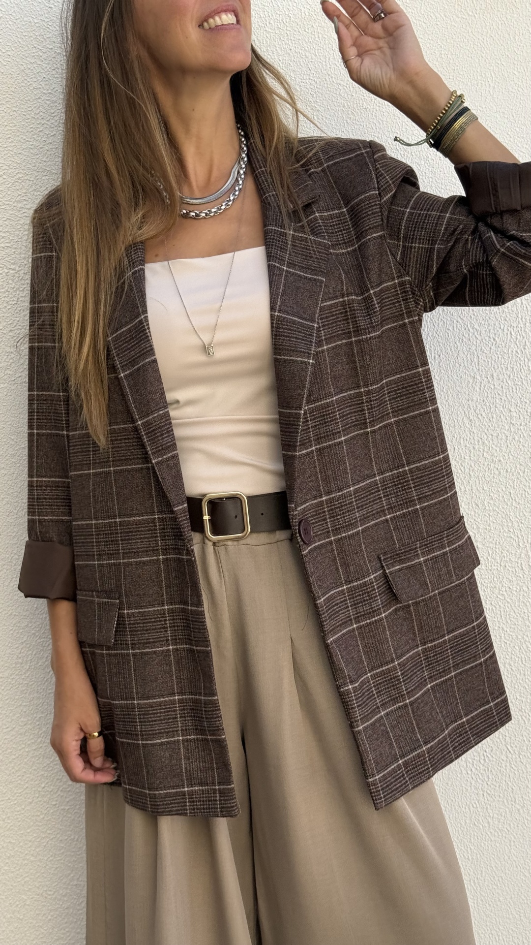 Blazer castanho às riscas, calças bege, top creme, acessórios metálicos e cinto castanho com fivela dourada.