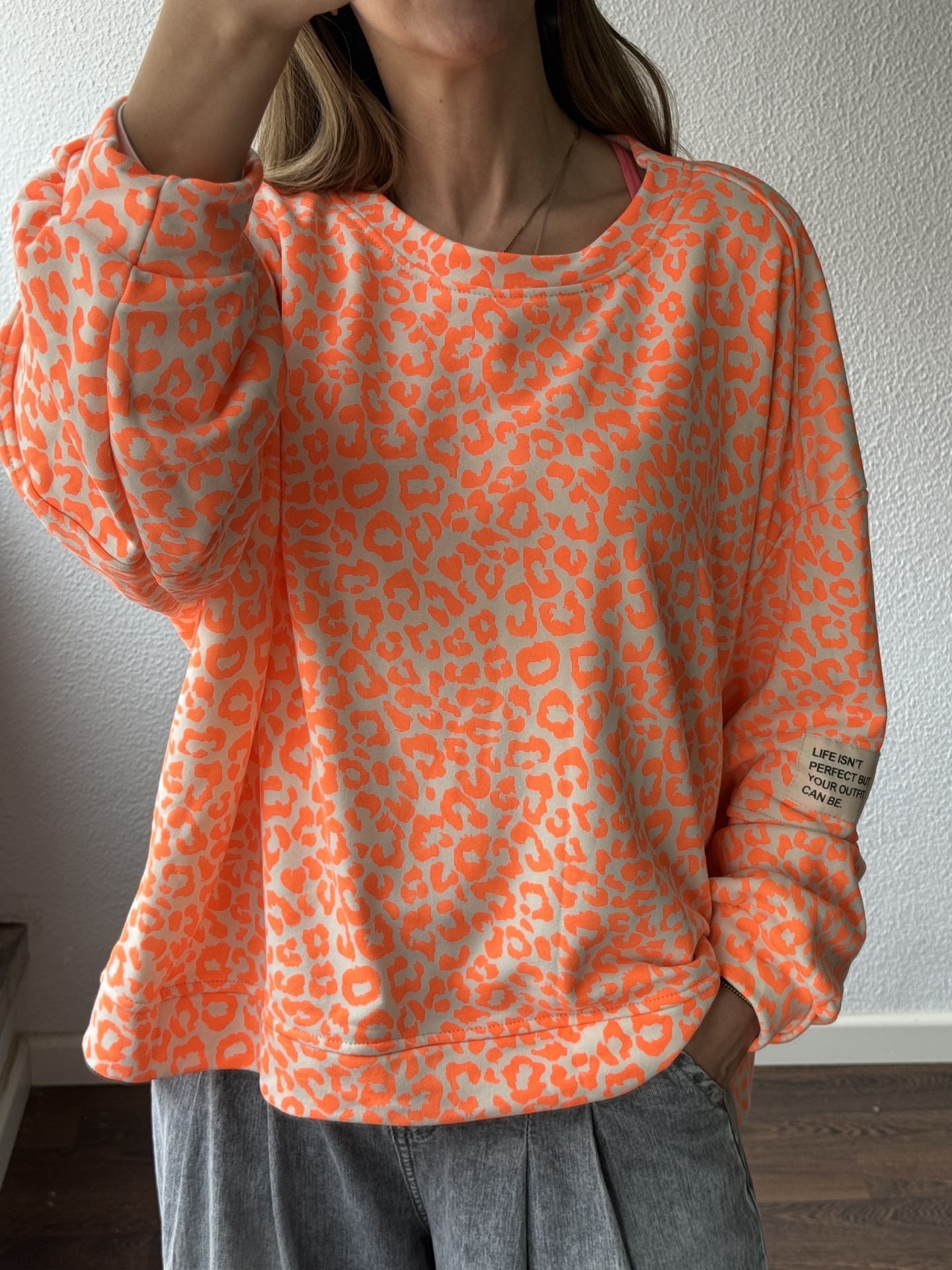 Sweatshirt padrão leopardo bege e laranja fluorescente com etiqueta escrita na manga