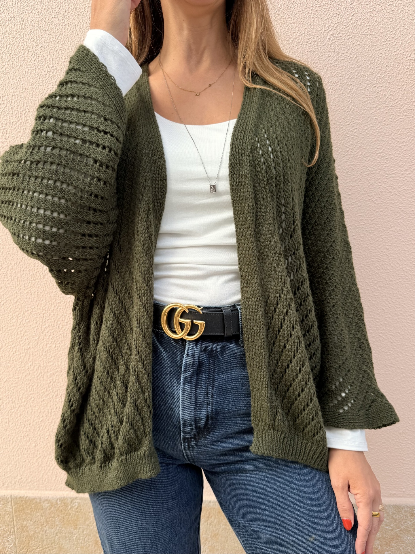 Cardigan verde musgo de malha, camisola branca, jeans azul e cinto preto com fivela dourada GG