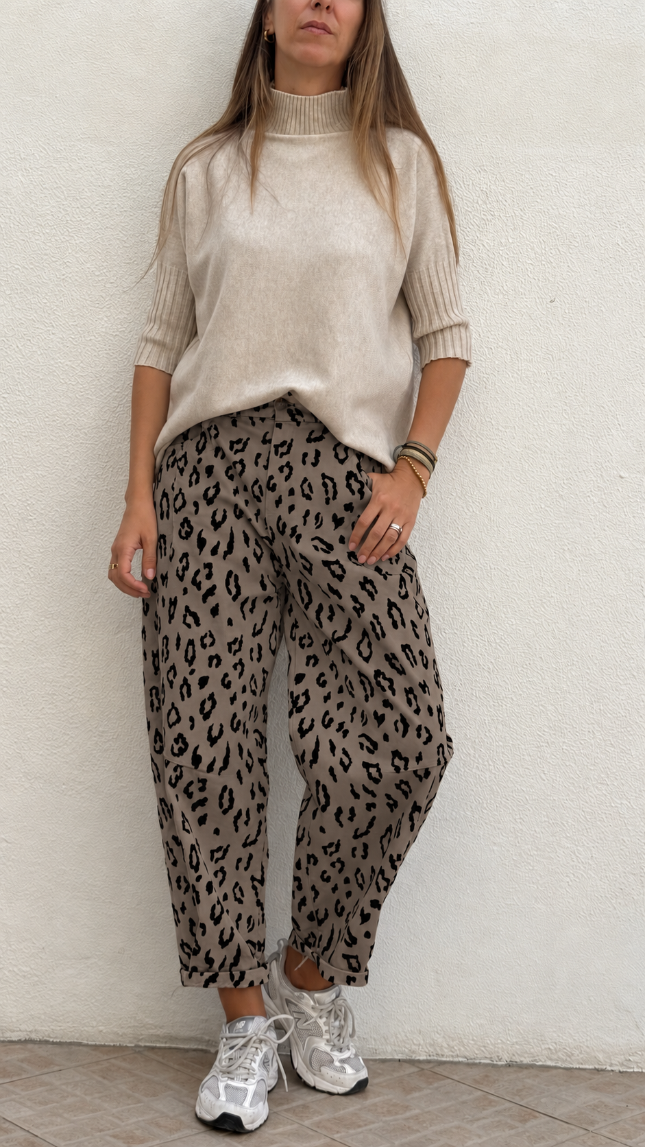 Mulher com camisola bege de malha e calças animal print com sapatilhas brancas