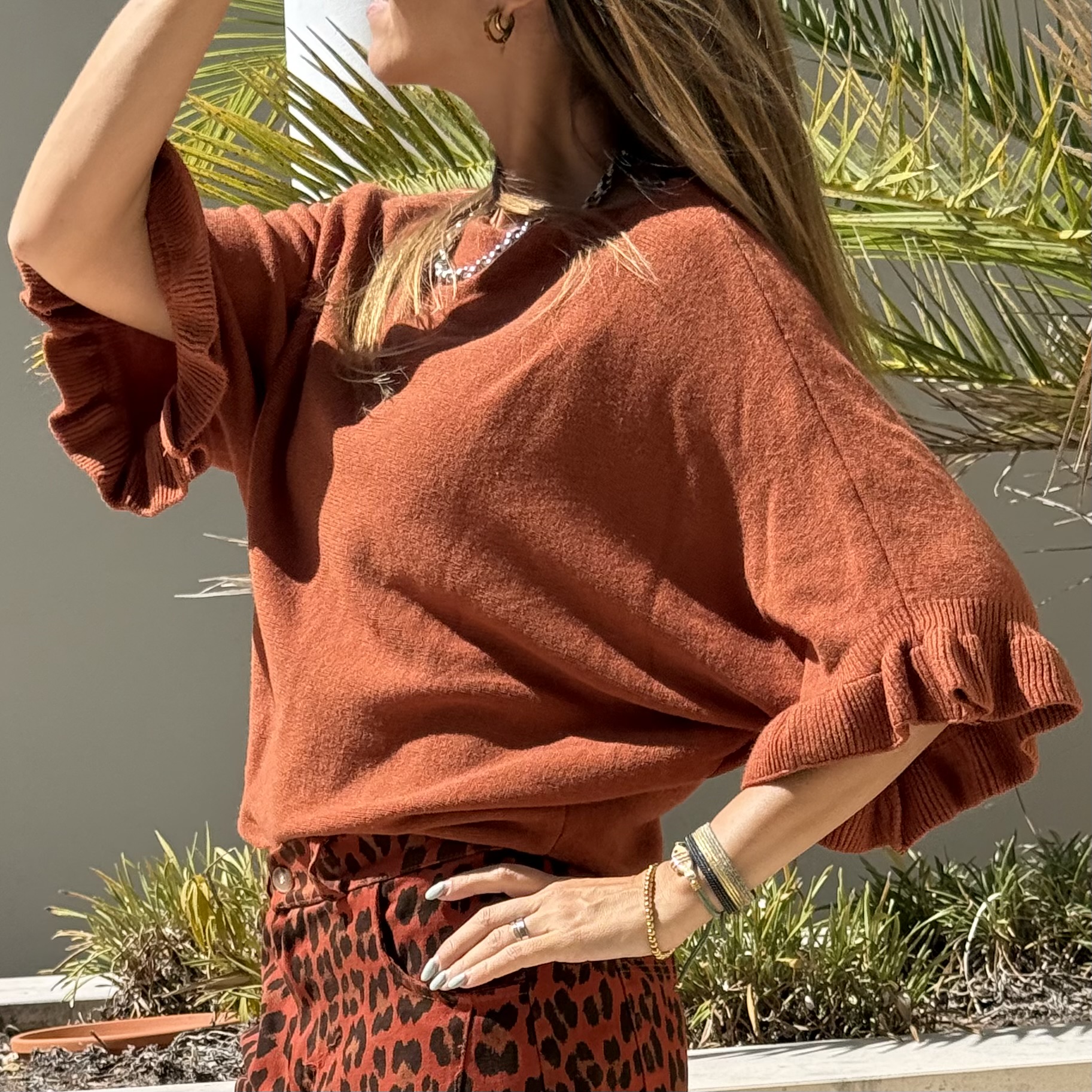 Blusa de malha cor tijolo com folhos nas mangas e calças padrão animal print.
