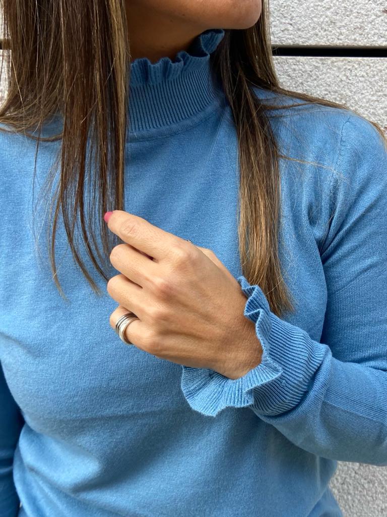 Camisola azul clara de malha com gola alta e punhos ondulados em mulher.