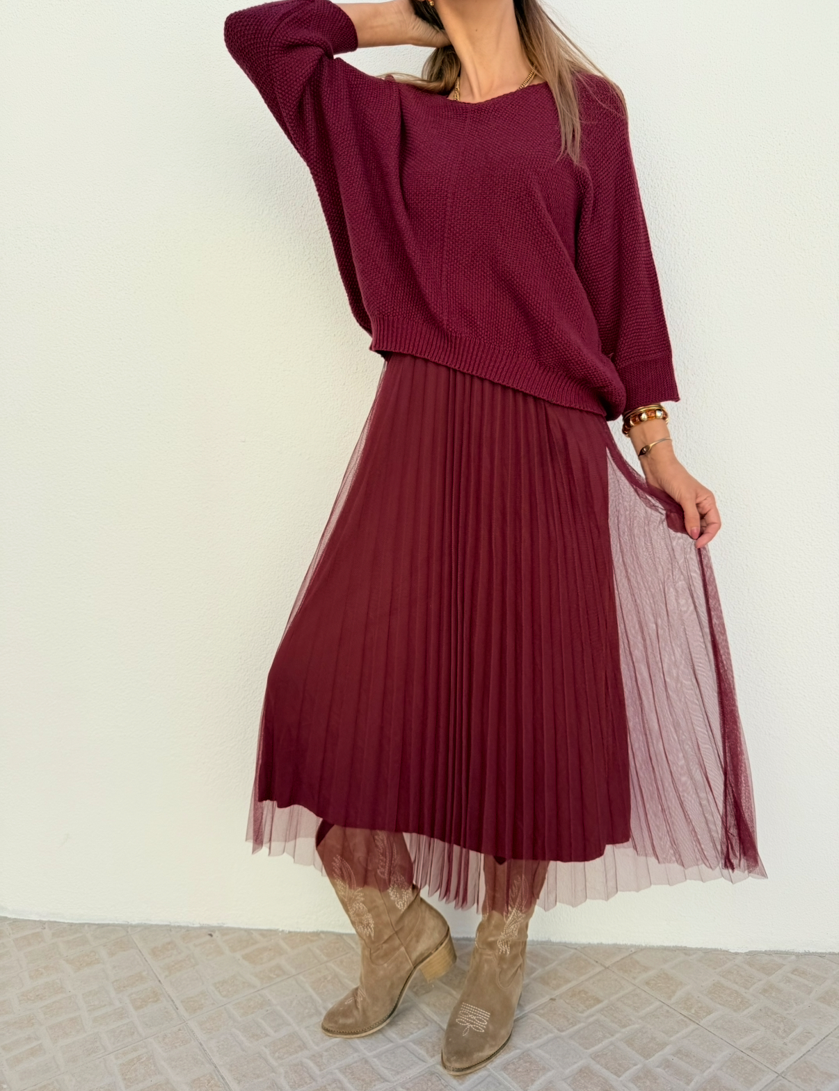 Conjunto feminino com camisola de malha borgonha, saia midi plissada de tule borgonha e botas cowboy bege