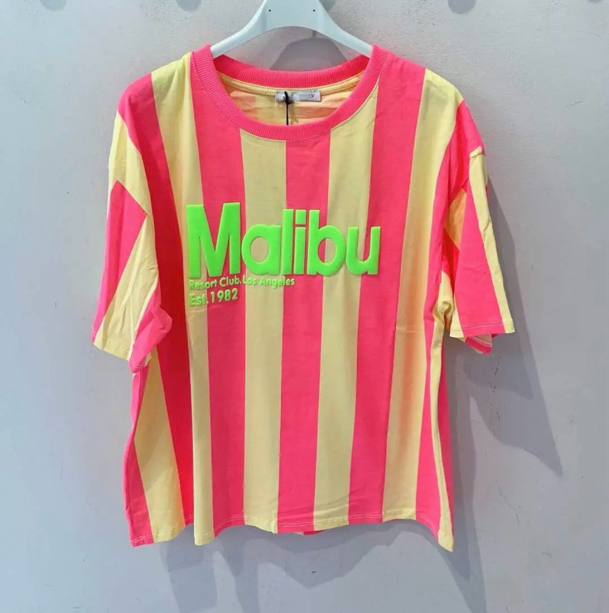 T-shirt de manga curta rosa e amarelo com texto verde pendurada