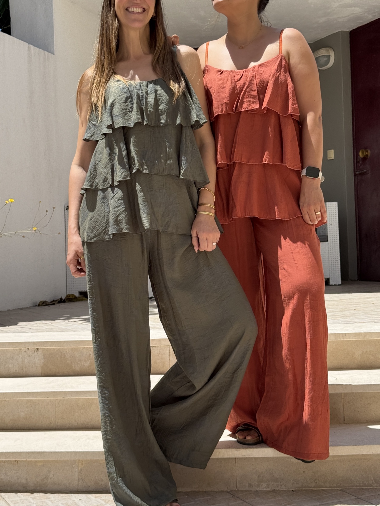 Dois conjuntos femininos com calças largas e tops com três camadas de folhos, um verde-acinzentado e outro laranja queimado.
