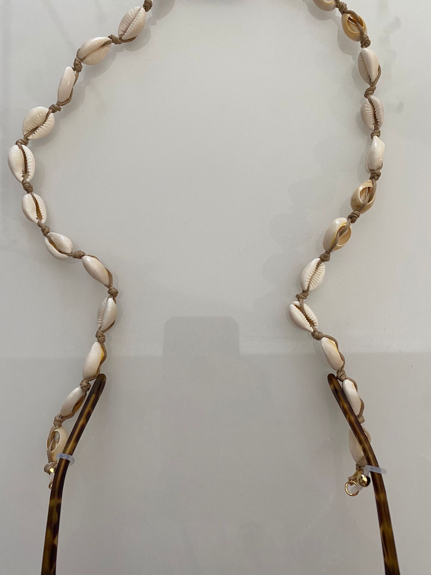Cordão para óculos com conchas e corda castanha ligado a armação tartaruga
