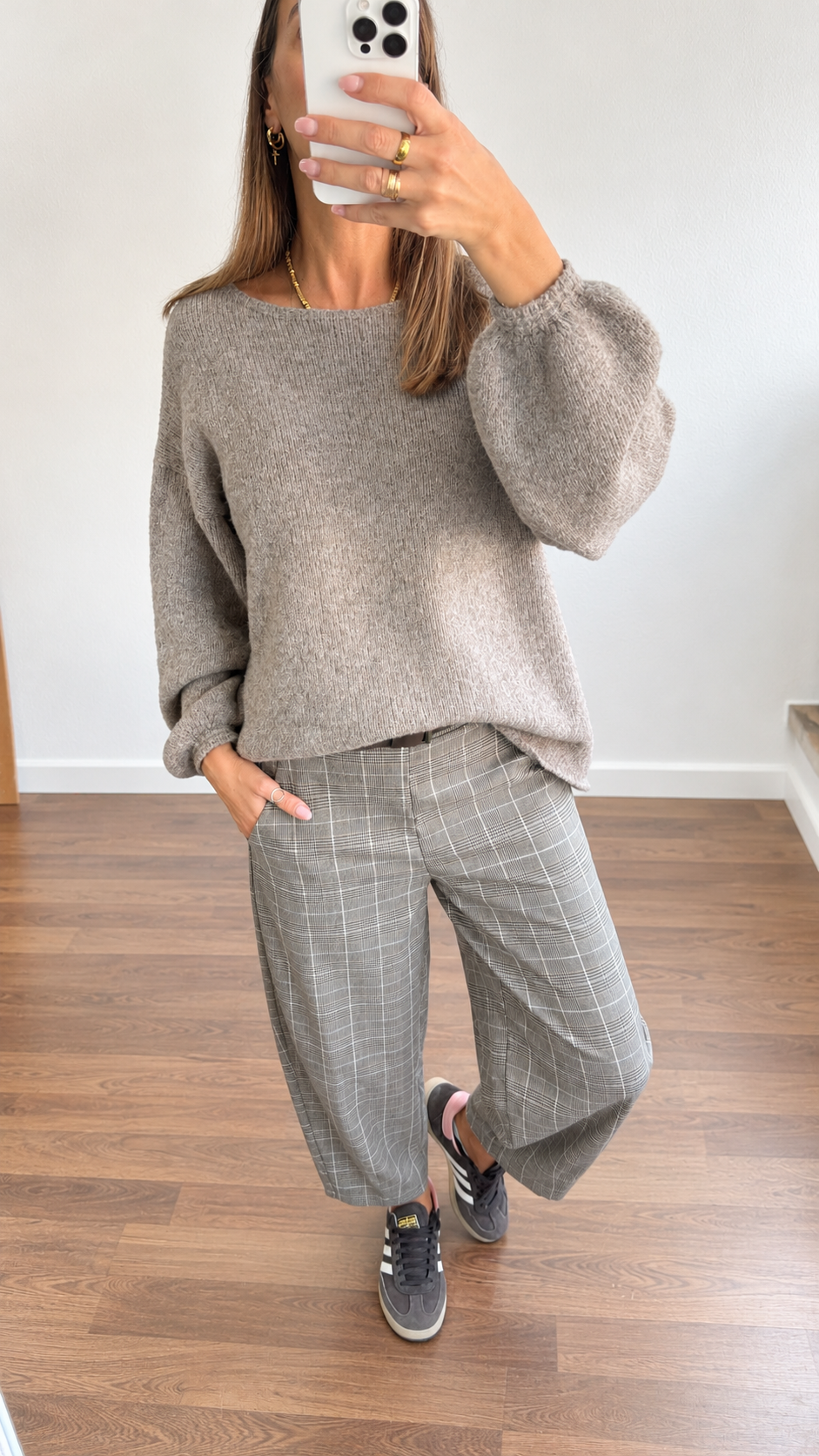 Roupa casual com camisola cinza, calças aos quadrados e ténis cinza em interior