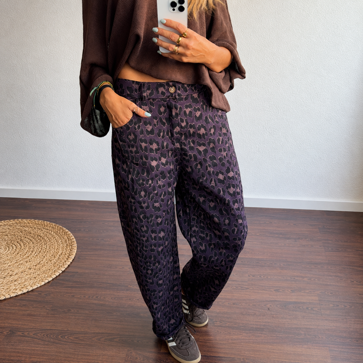 Calças com padrão animal print roxo e preto, usadas com camisola castanha e sapatilhas cinzentas