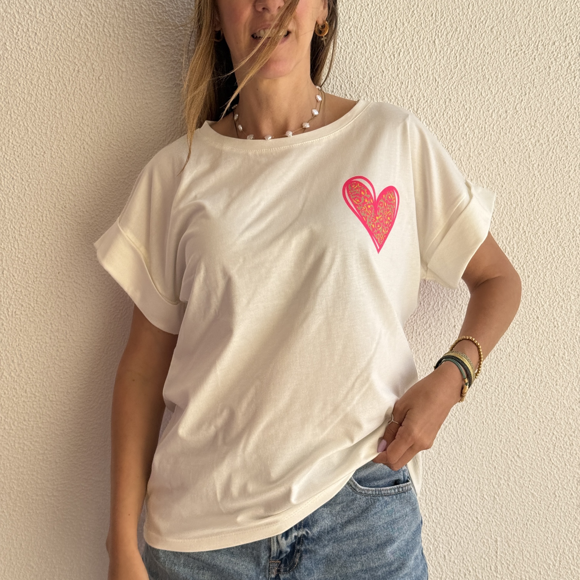 Mulher vestindo t-shirt branca com padrão de coração cor-de-rosa e amarelo