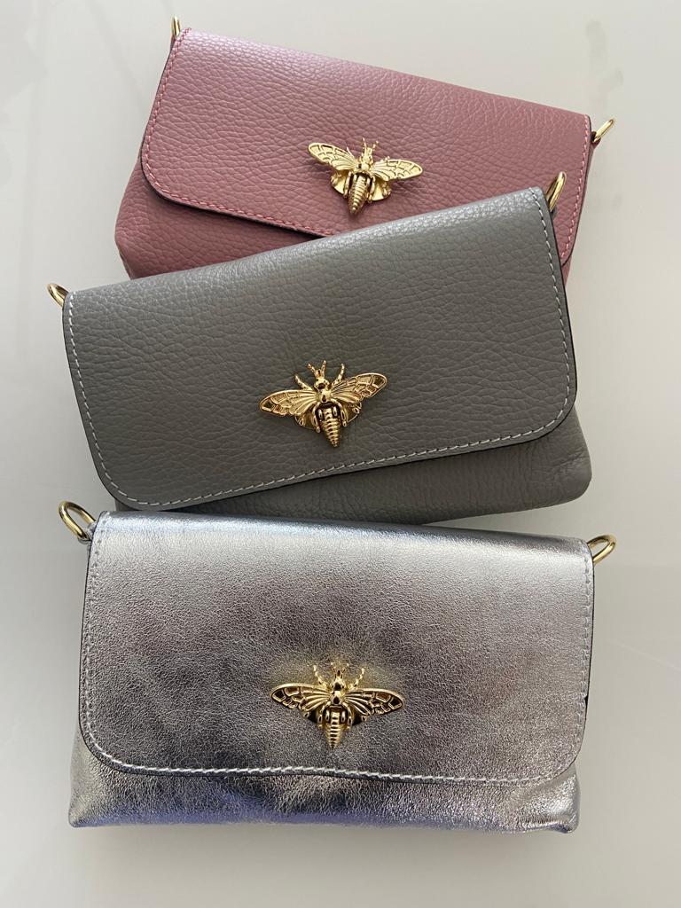 Três malas pequenas em pele com abelhas douradas no fecho, em rosa, cinza e prateado