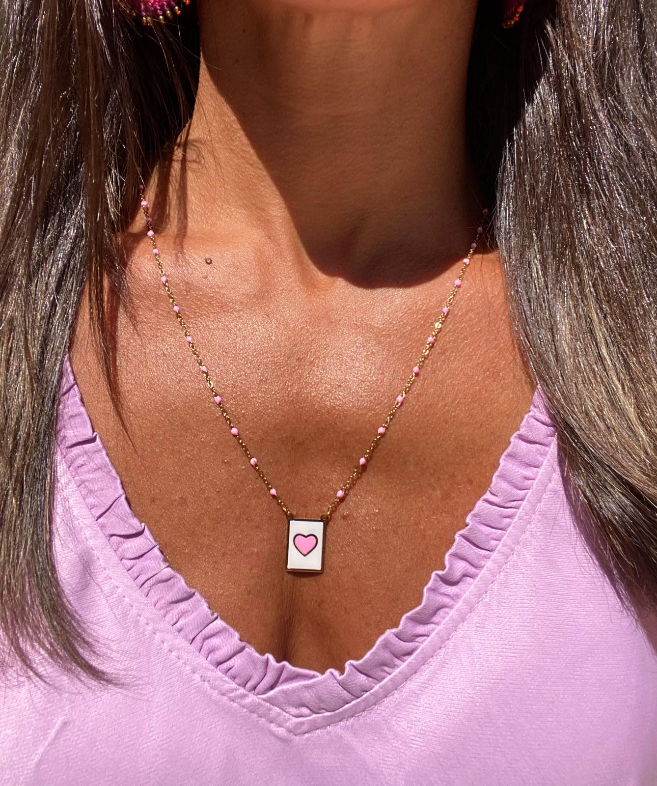 Colar com pendente retangular branco com coração rosa e corrente de contas pequenas em tons rosa e dourado
