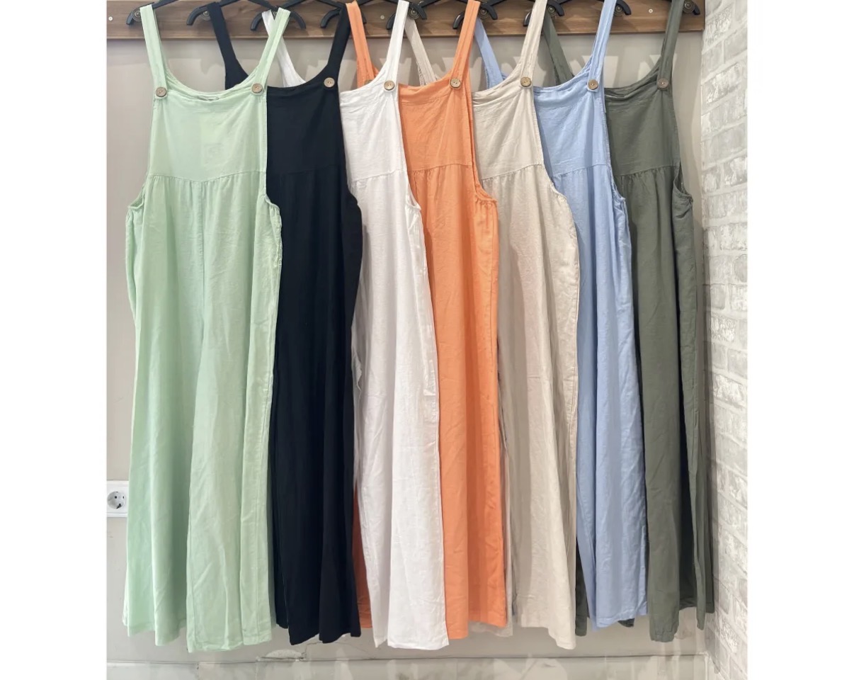 Vestidos longos coloridos de alças finas com botões de madeira pendurados em cabideiro.