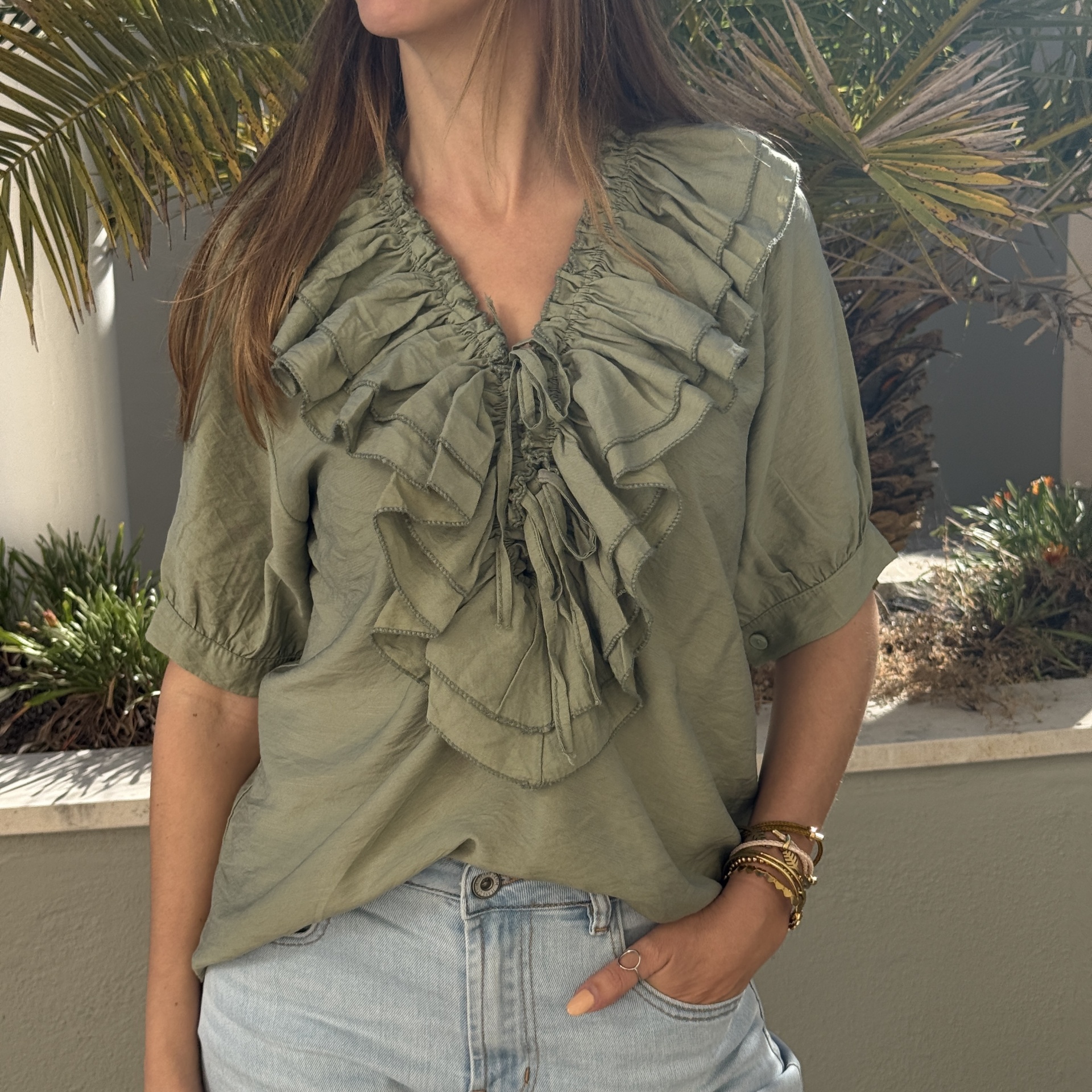 Blusa verde-oliva com folhos e calças de ganga claras